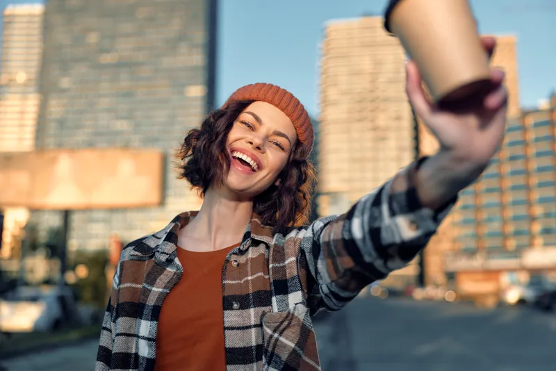 woman coffee smile urban portrait beanie happy candid captured in golden hour glow, authenticity and mindful living. Emotional storytelling of a joyful city lifestyle with takeaway cup