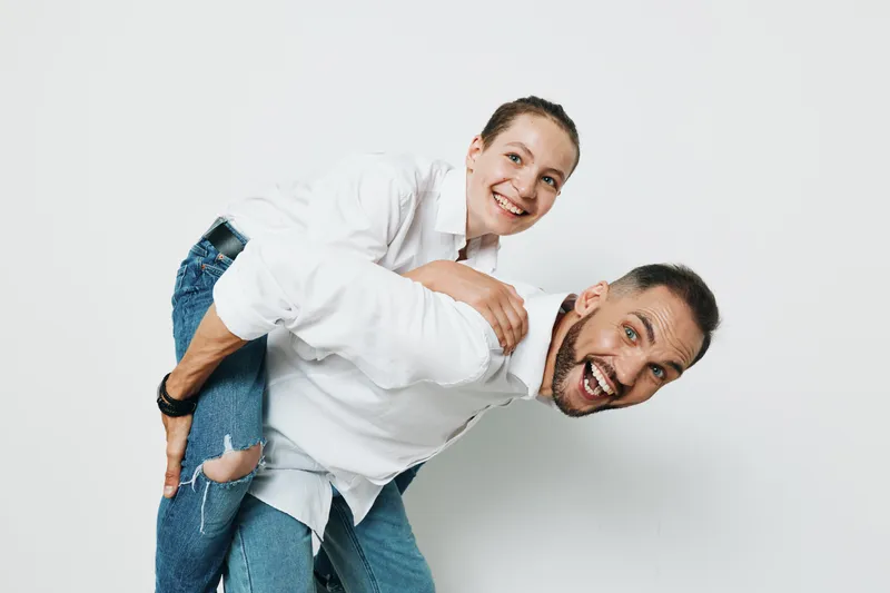 A professional man in a business context is lifted by a colleague against an isolated colored background, conveying teamwork, confidence, and positive emotion in a corporate scene.