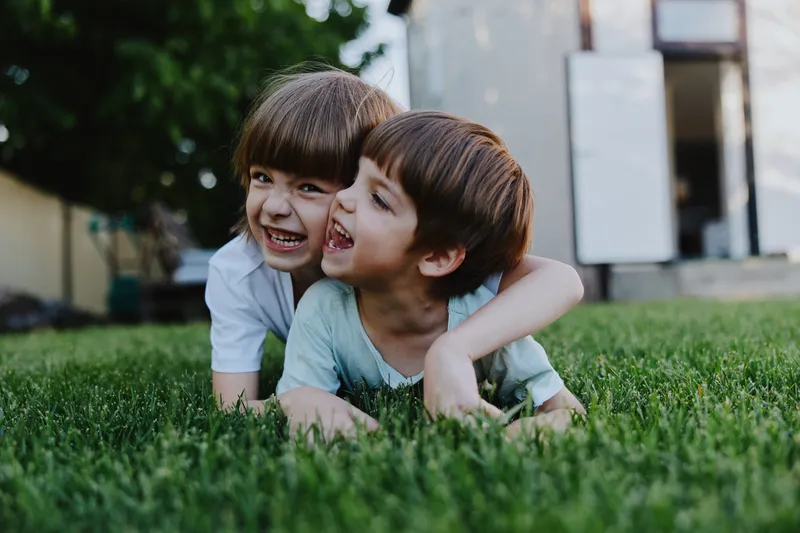 Playful children enjoying a sunny day outside, showcasing laughter and joy in a vibrant green backyard, capturing the essence of childhood fun.