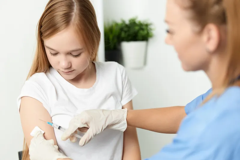 Врач-женщина делает ребенку укол для вакцинации
