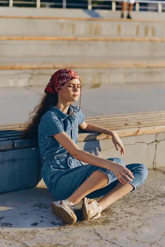 Lifestyle woman in modern boho-western denim street style relaxing outdoors with film color tones and casual comfortable outfit during sunny day