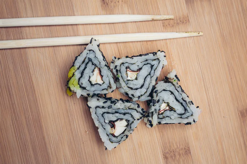 Роллы суши с палочками на деревянной доске, японская кухня