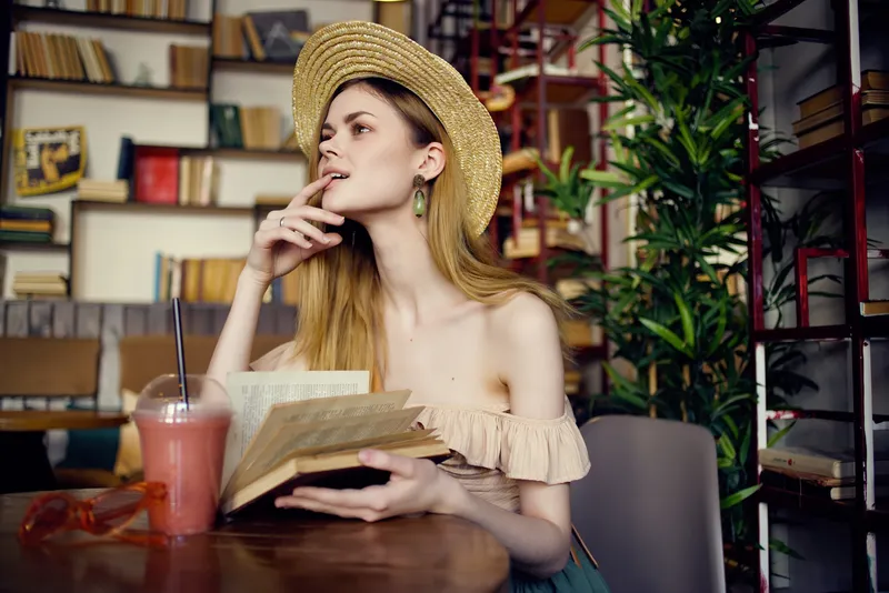 Красивая женщина читает книгу в кафе, отдыхая