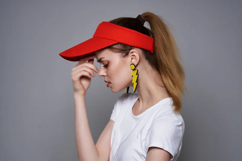 Весёлая девушка в летней одежде, модных жёлтых серьгах позирует на светлом фоне