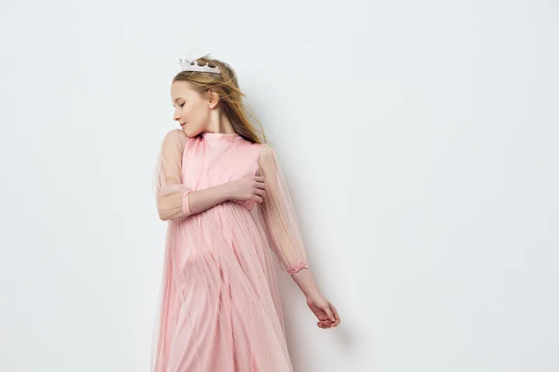 Young girl in a pink tulle dress, embodying innocence and joy, posed elegantly against a neutral background, perfect for fashion or childhood themes