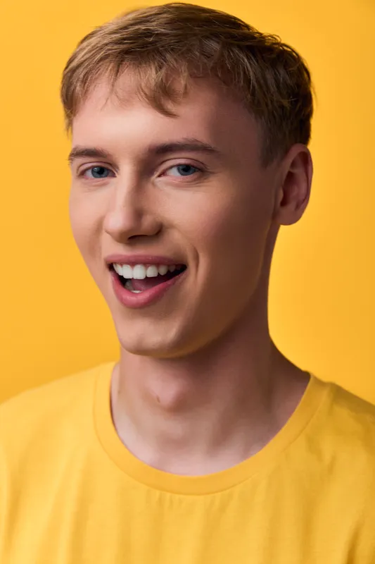 Smiling man, yellow shirt, yellow background, happiness, cheerful expression, casual style in a studio setting, ideal for lifestyle, fashion or promotional photography.