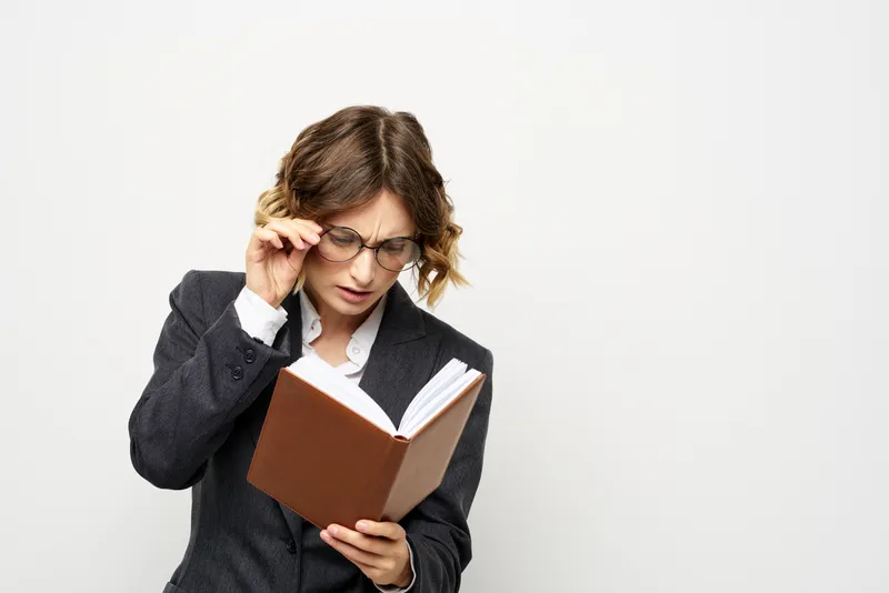 Женщина за работой с книгой в руке на светлом фоне