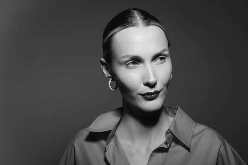 Portrait of a fair skinned white woman with slicked back hair and hoop earrings in studio lighting. Concept of elegance, fashion, and minimalistic style.