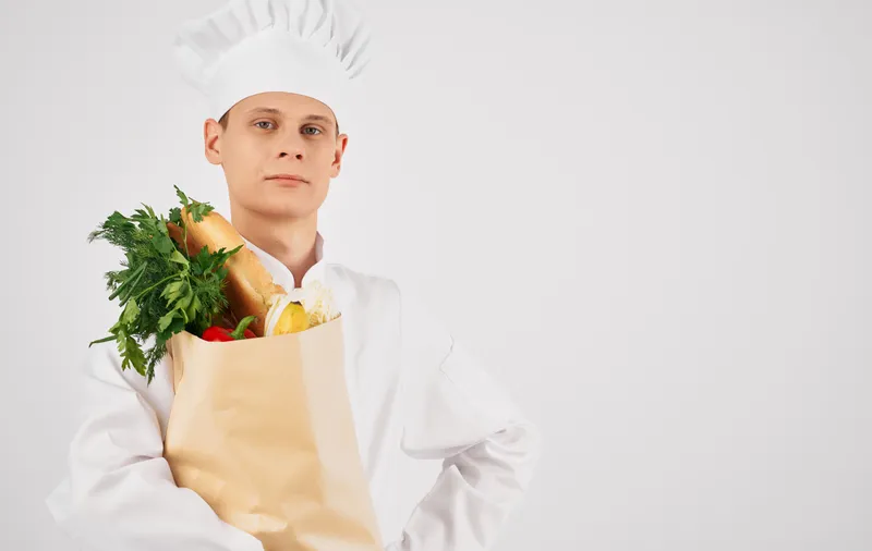 Шеф-повар с продуктовым набором в процессе приготовления еды в профессиональном ресторане
