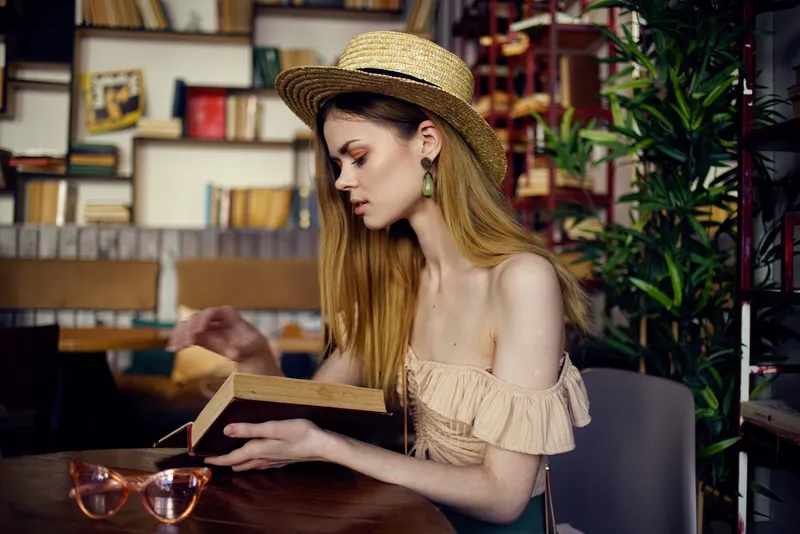 Женщина читает книгу, отдыхая в кафе, наслаждаясь напитком