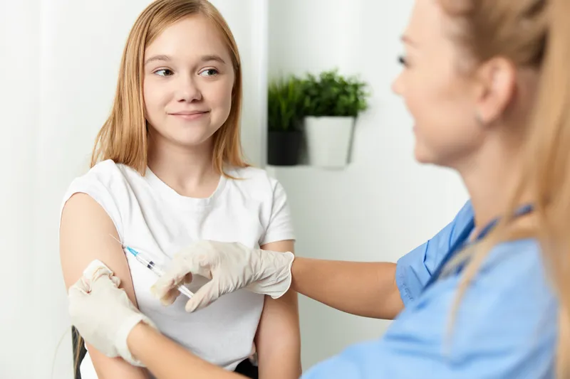 Женщина-врач делает девочке укол в руку, вакцинация