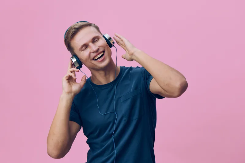 happy smiling young man wear headphones listen music enjoy wireless audio isolated pink background digital detox concept