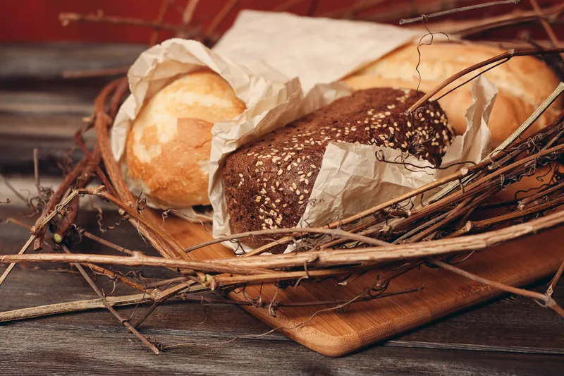 Выпечка буханки хлеба, мучной продукт в гнезде на деревянном столе