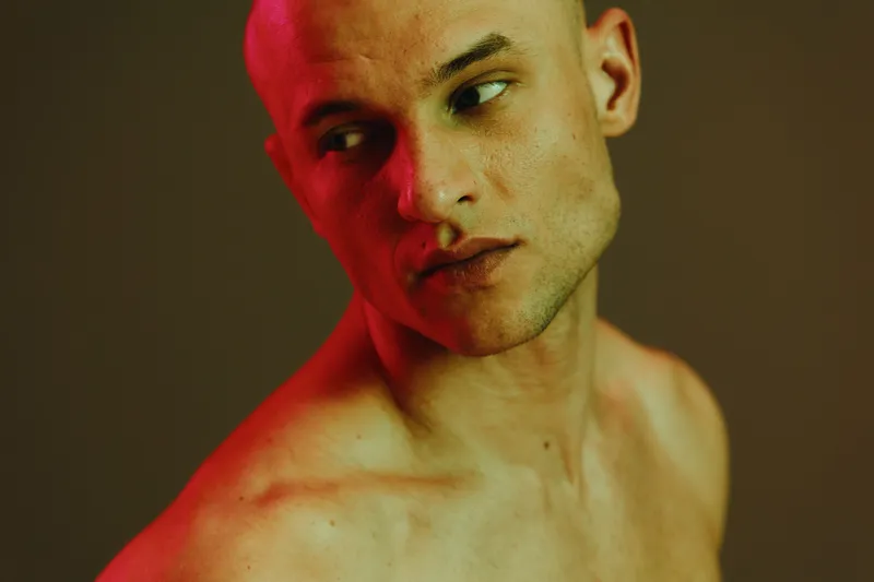 Artistic portrait of a pensive man with striking lighting, featuring a captivating interplay of red and green hues, creating an intense atmosphere.