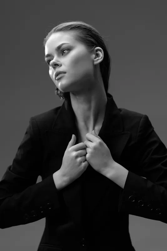 Black and white portrait of a serious woman in a blazer with thoughtful expression and elegant posture