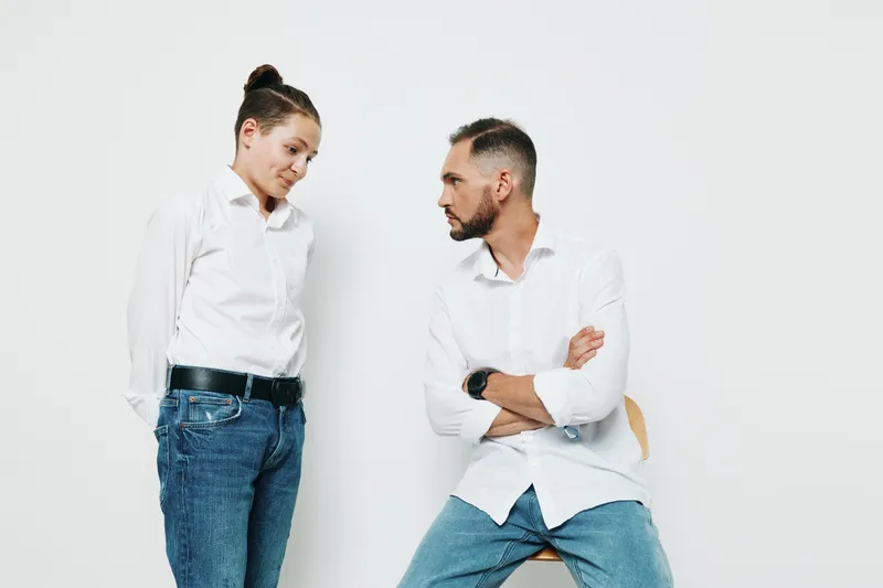 A professional man stands with arms crossed in a clean studio against a solid white background, projecting confidence, focus, and calm leadership.