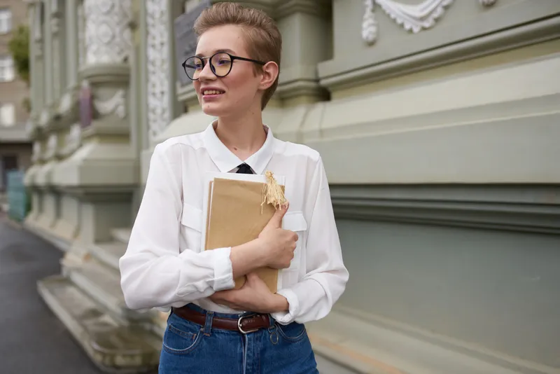 Симпатичная женщина с книгой в руках на открытом воздухе читает, занимается самообразованием