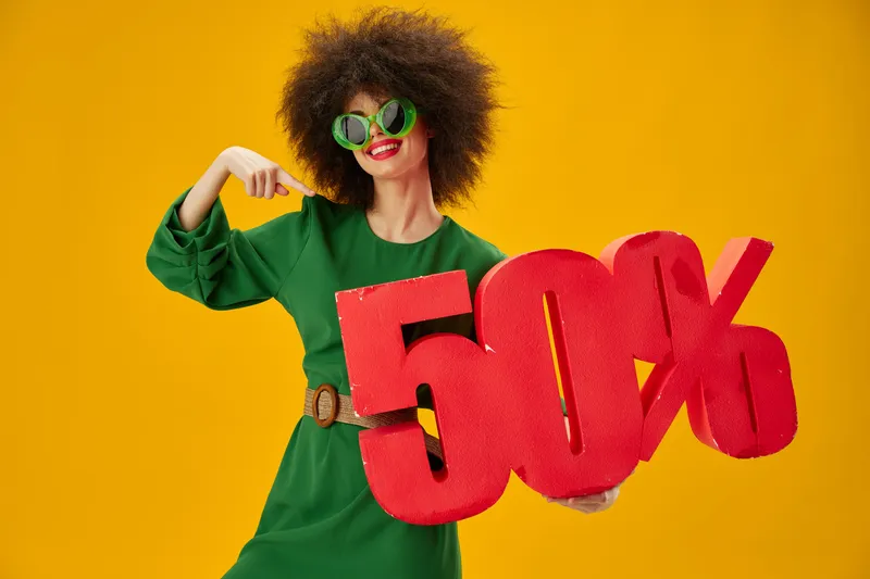 Симпатичная женщина держит красную табличку со скидкой 50% на рекламном жёлтом фоне