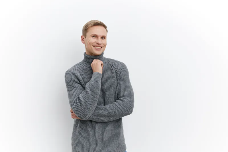 Smiling casual man in gray sweater standing isolated on white background with happy expression using laptop for digital nomad lifestyle cyber security and AI communication concept
