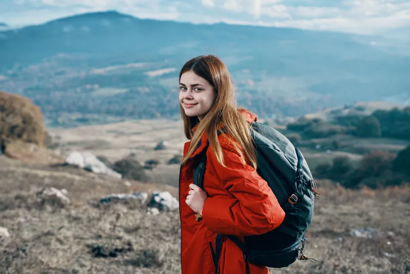 Женщина-туристка в куртке и с рюкзаком отдыхает в горах, пейзаж, отдых, модель