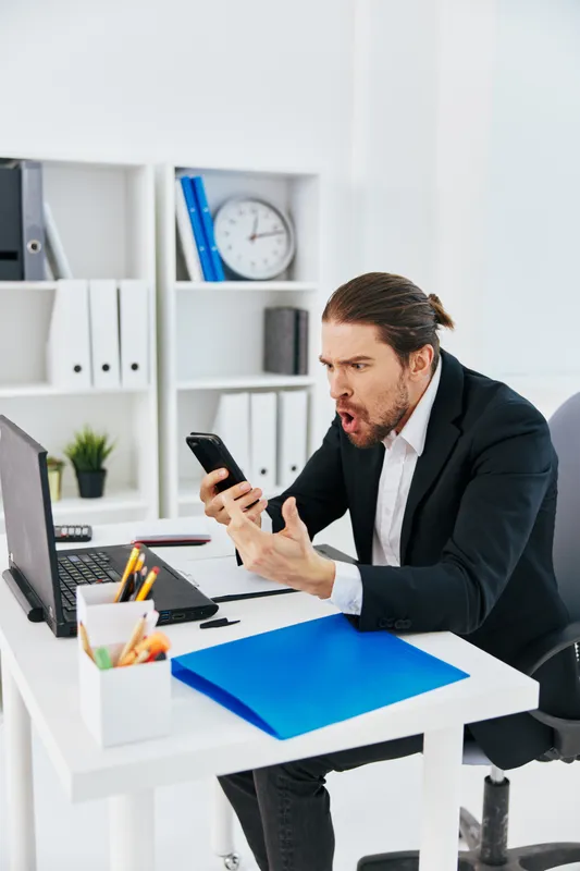 Менеджер работает в офисе с документами, держа в руке телефон, начальник