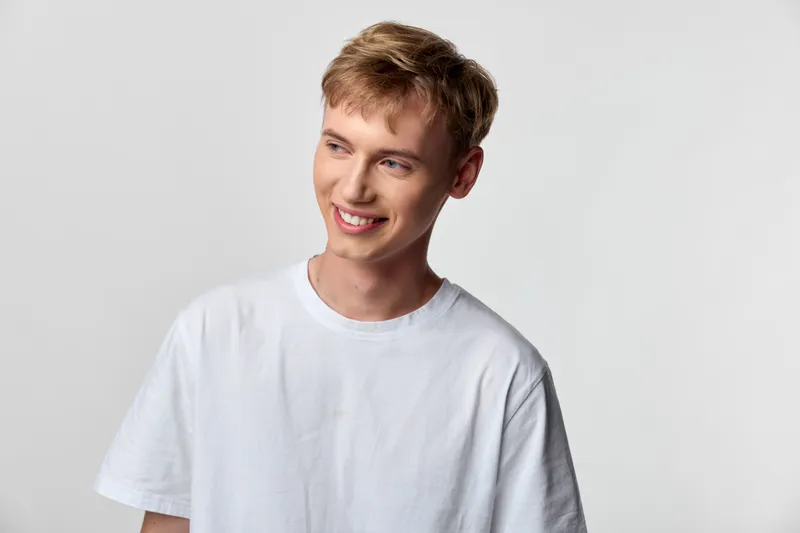 Male with a friendly smile wearing a white tshirt in a bright studio, casual style and a relaxed pose, showcasing approachability, youth energy, simple fashion and clean visuals