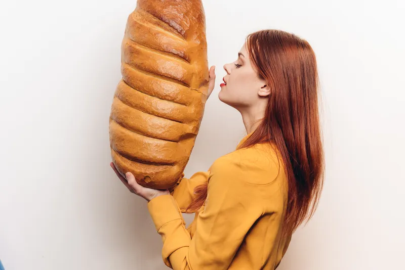 Эмоциональная женщина с большим бутоном на светлом фоне, в желтой рубашке, с ярким макияжем