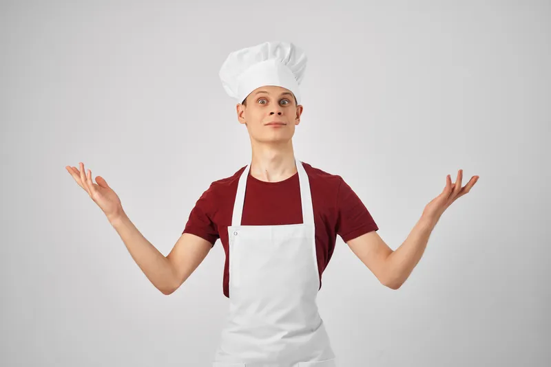 Мужчина-повар в колпаке на голове работает на кухне