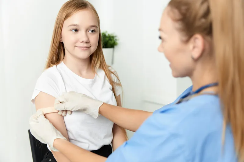 Врач заклеивает руку лейкопластырем после вакцинации в больнице