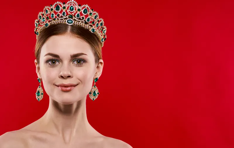 Портрет красивой женщины с диадемой на голове на красном фоне