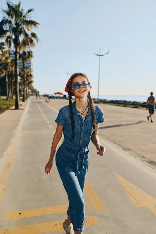 modern boho-western denim street style woman smiling outdoors with sunglasses film color bright sunny day casual outfit