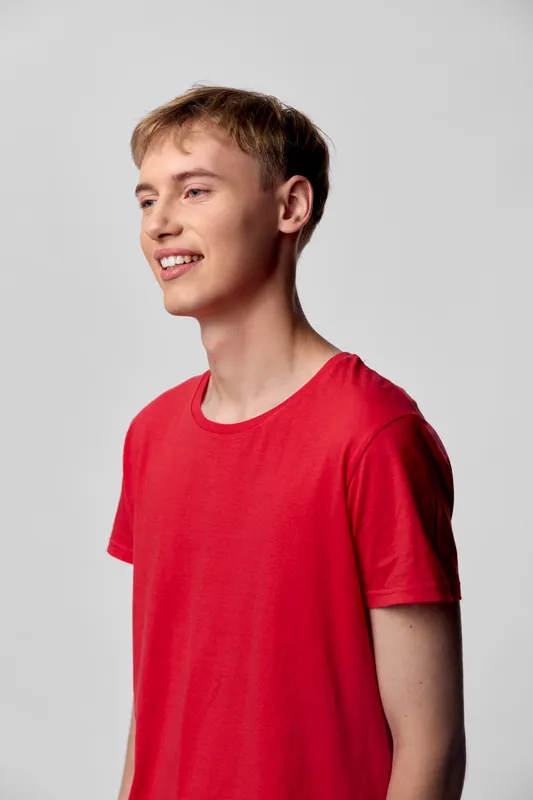 Smiling young man wearing a red tshirt in a studio setting with a clean background, casual style and confident vibe, highlighting fashion and lifestyle imagery suitable for product, advertising and