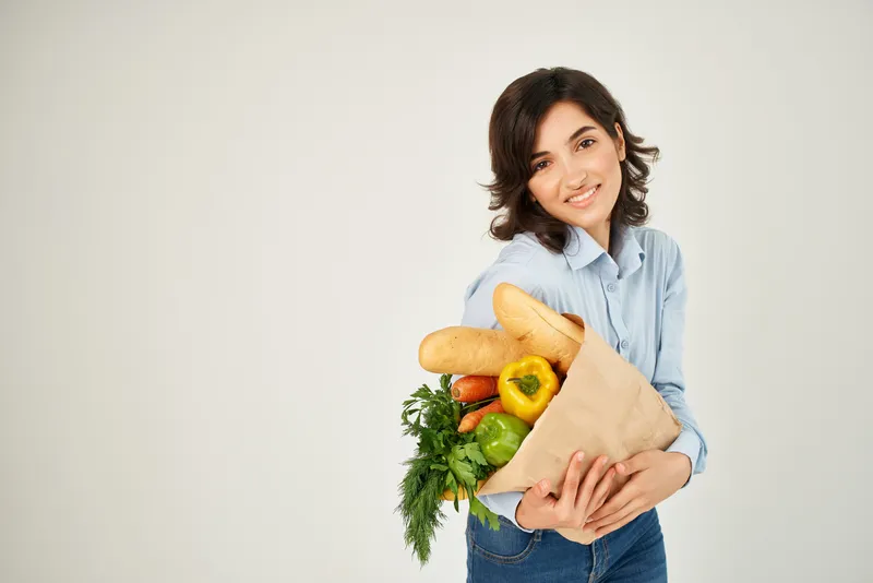Весёлая брюнетка с пакетом продуктов для здорового питания
