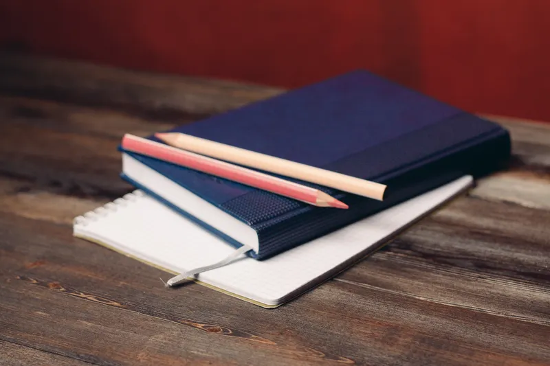 Книга, блокнот, карандаши и офисные документы на деревянном столе
