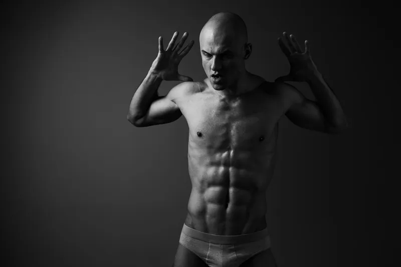 Powerful man in black and white showing intense emotions, showcasing strength and determination. Captures the essence of human expression and physicality.