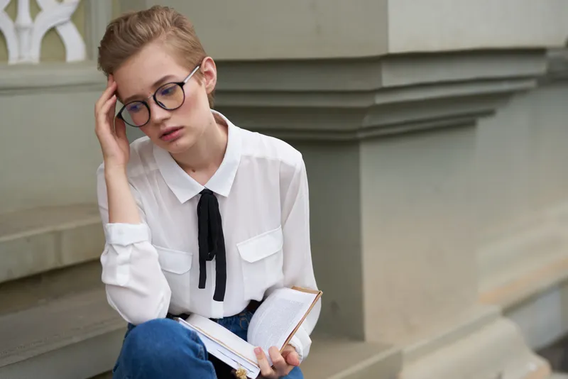 Студент с книгой в руках на открытом воздухе, читает, стиль жизни