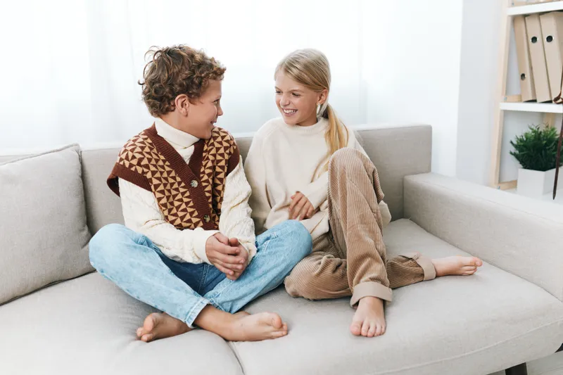 Authenticity shines through in a candid home scene featuring school age children enjoying a playful, wholesome moment on a cozy living room sofa.