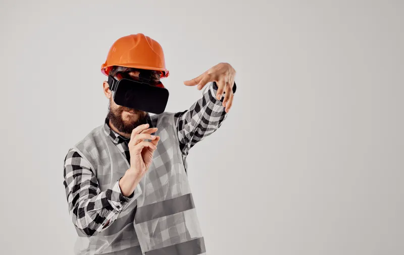 Строитель в оранжевой каске и 3D-очках жестикулирует руками