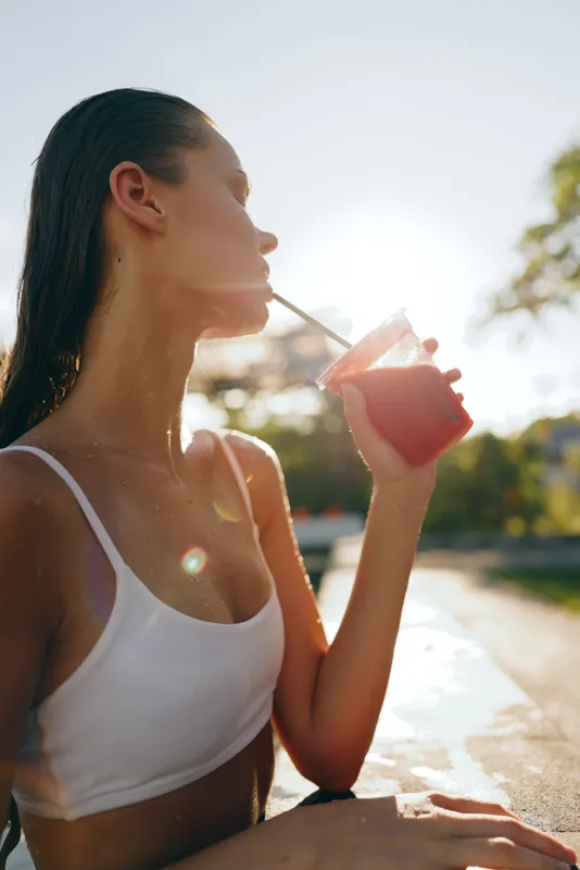 woman drink summer outdoors sunlight water casual lifestyle leisure candid in a sunny outdoor setting, relaxed vibe as she enjoys a beverage in daylight