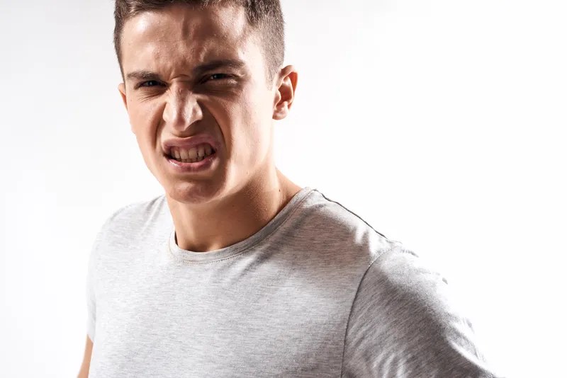 Спортивный мужчина в белой футболке на светлом фоне жестикулирует руками, обрезанный вид, место для копирования