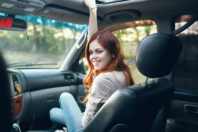Женщина с открытым окном на переднем сиденье автомобиля жестикулирует руками