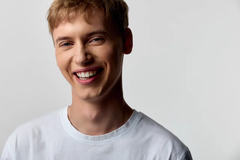 Smile, man, casual, white t shirt, studio light, happy, youthful, fresh face, approachable, warmth in a bright studio setup for lifestyle and branding use