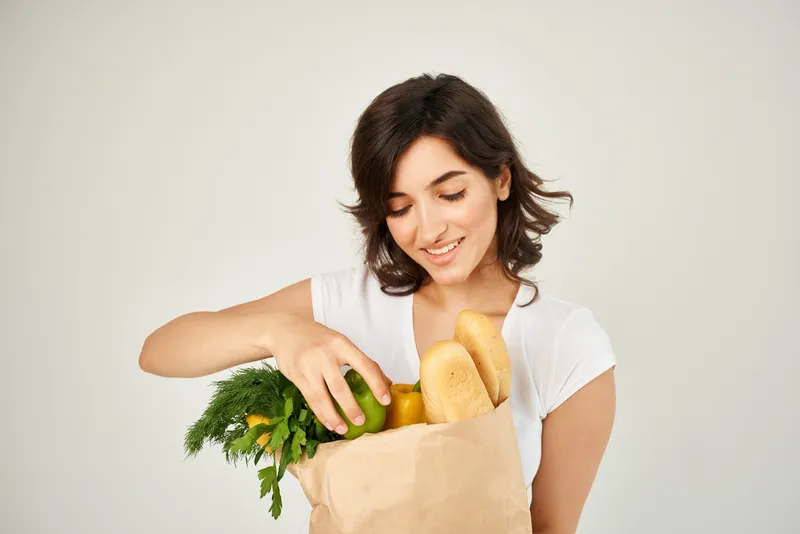 Весёлая брюнетка с пакетом продуктов, доставка из супермаркета