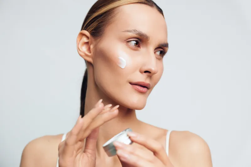 Skincare routine portrait of a woman applying moisturizer cream to her face, a closeup of facial care, showcasing beauty, hydrated skin, fresh glow and healthy complexion