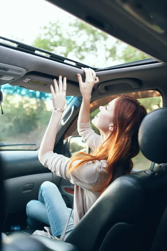 Женщина с открытым окном на переднем сиденье автомобиля жестикулирует руками, интерьер салона, попутчица