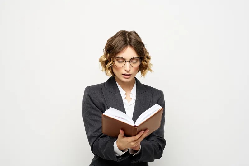 Женщина за работой с книгой в руке на светлом фоне