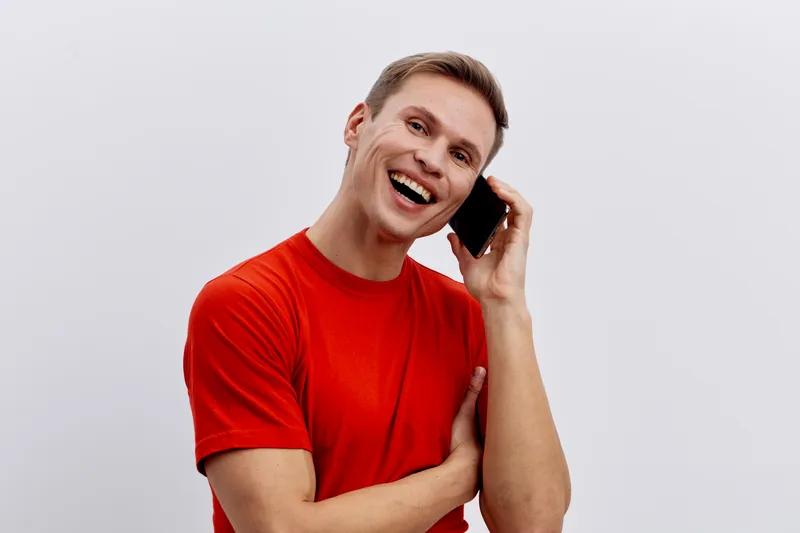 cheerful smiling young man using phone talking in video call digital nomad concept casual red t-shirt white background