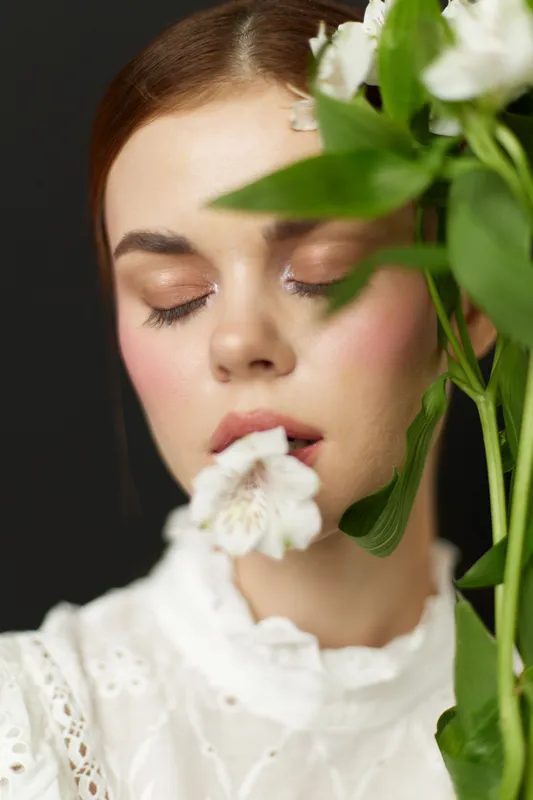 Female model with closed eyes, holding a flower, symbolizes tranquility and femininity, perfect for wellness and beauty concepts
