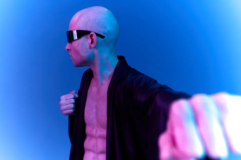 Athletic man in black robe showcasing determination and strength with a powerful pose. The vibrant light adds a dynamic, energetic feel to the scene.