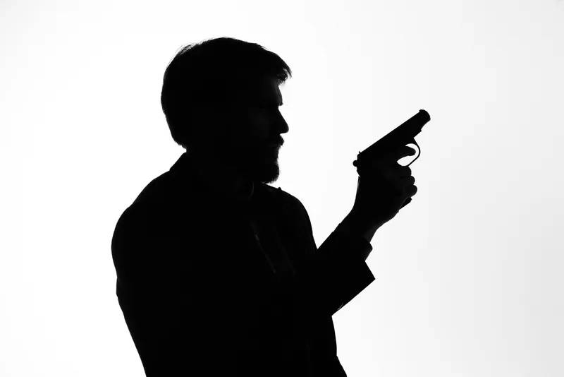 Силуэт мужчины с оружием в руках, передающий эмоции, позирует в студии